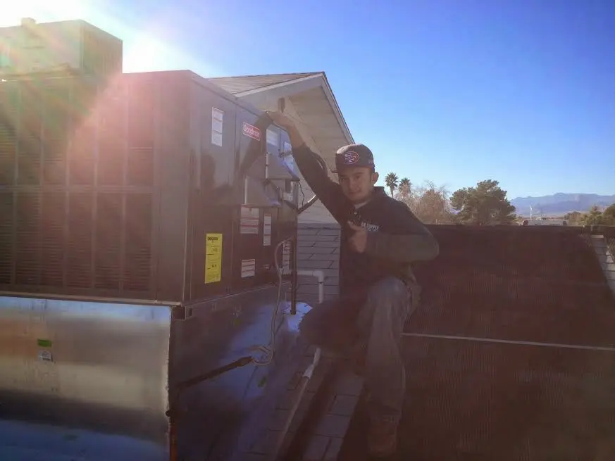 HVAC technician performing AC Tune-Up on a rooftop unit in Brookhaven